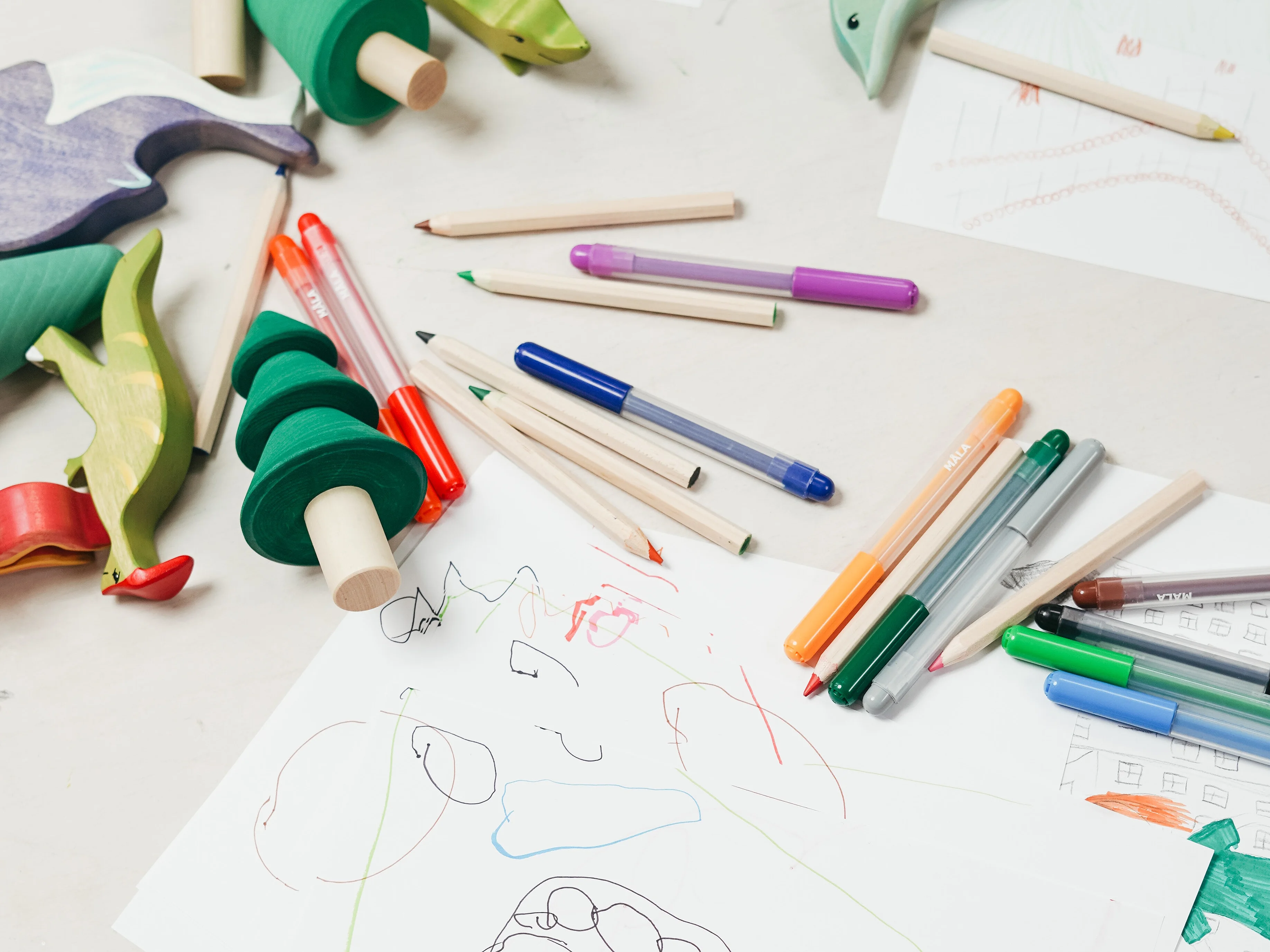 Pädagogische Werkstatt Auf einem Tisch liegen verschiedene Stifte und beschriebenes Papier