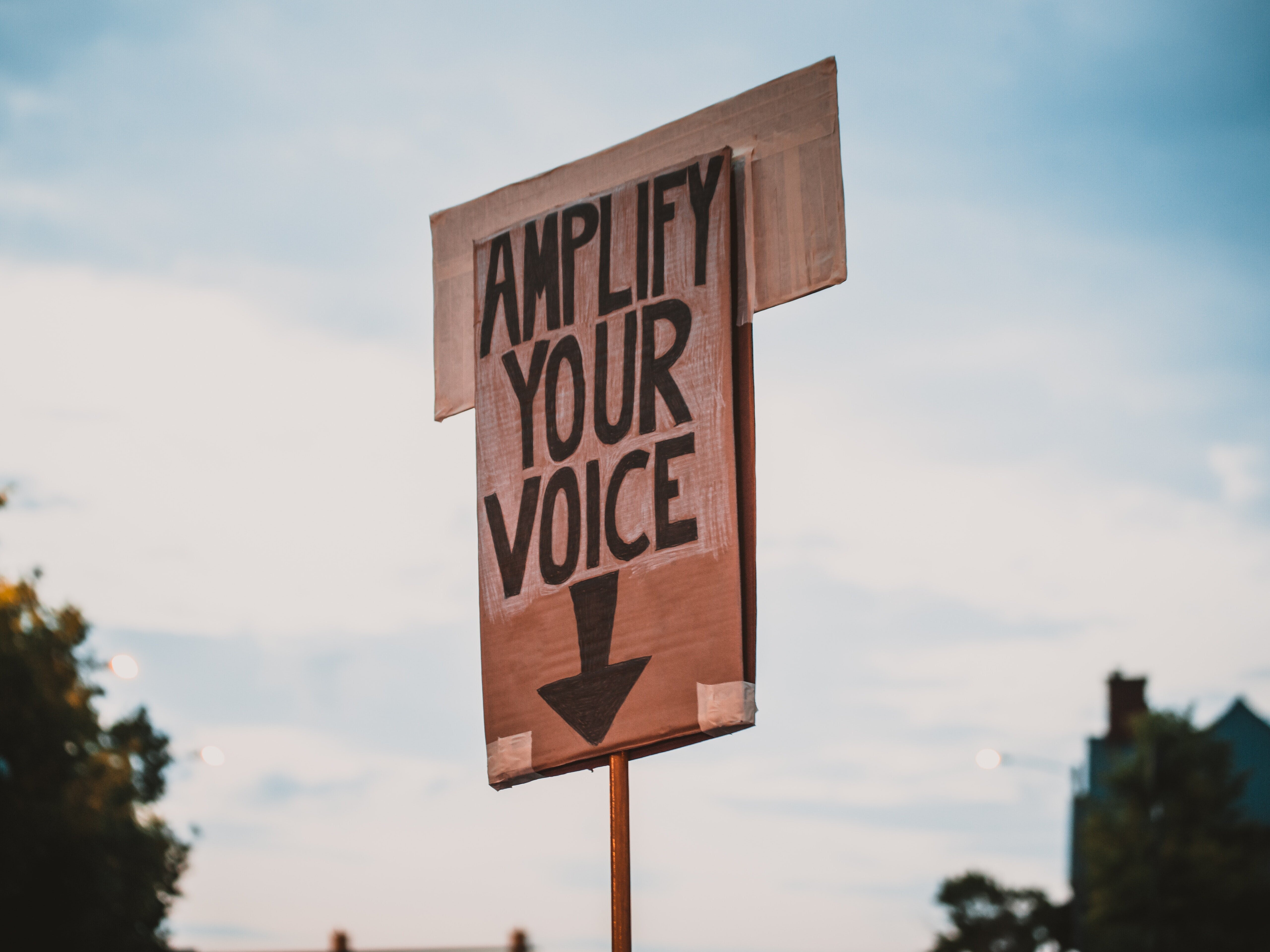 Ein Schild mit der Aufschrift "Amplify your voice" und einem Pfeil, der nach unten zeigt