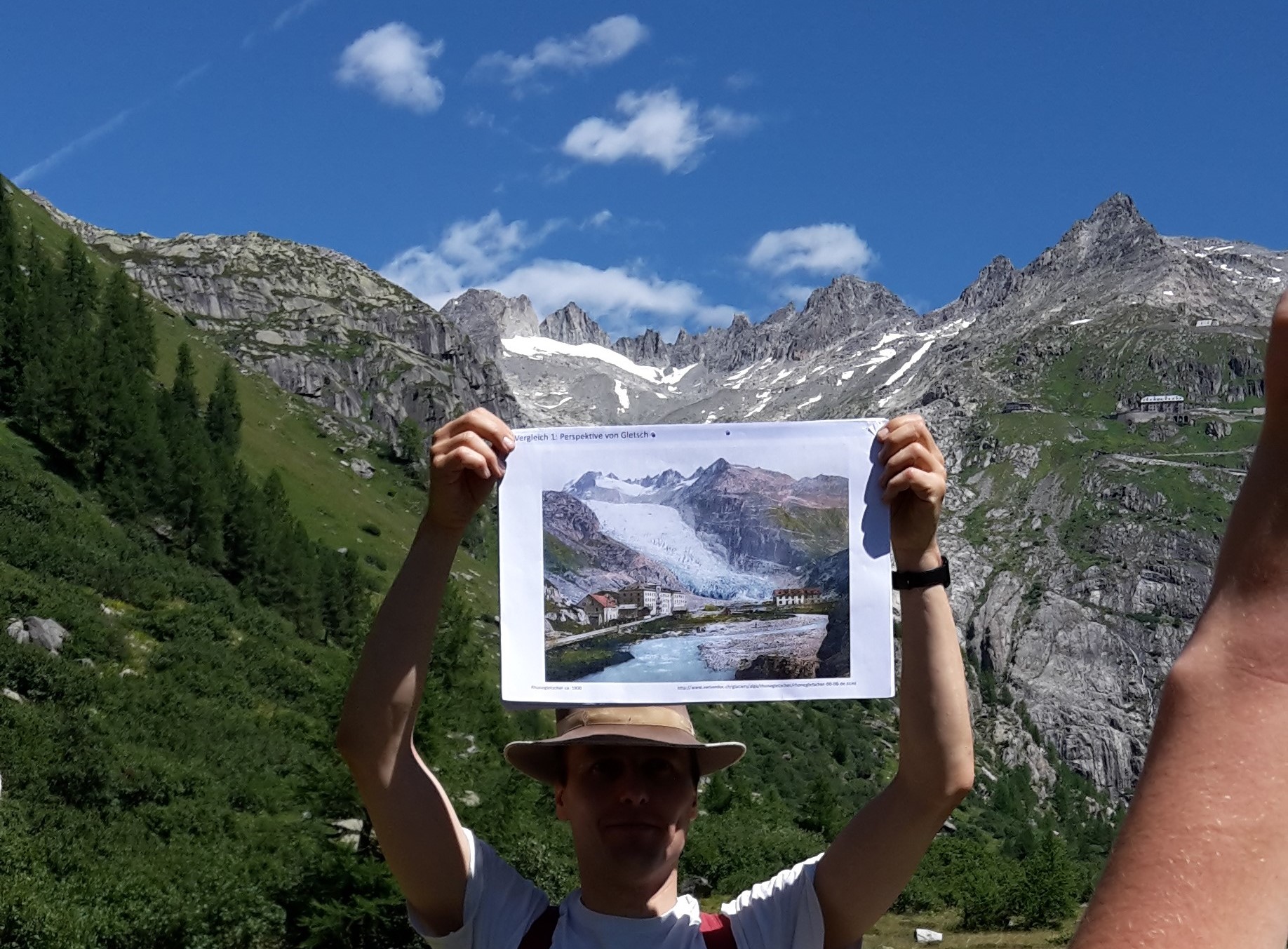 Dozent, der Postkarte vor Bergen hochhält