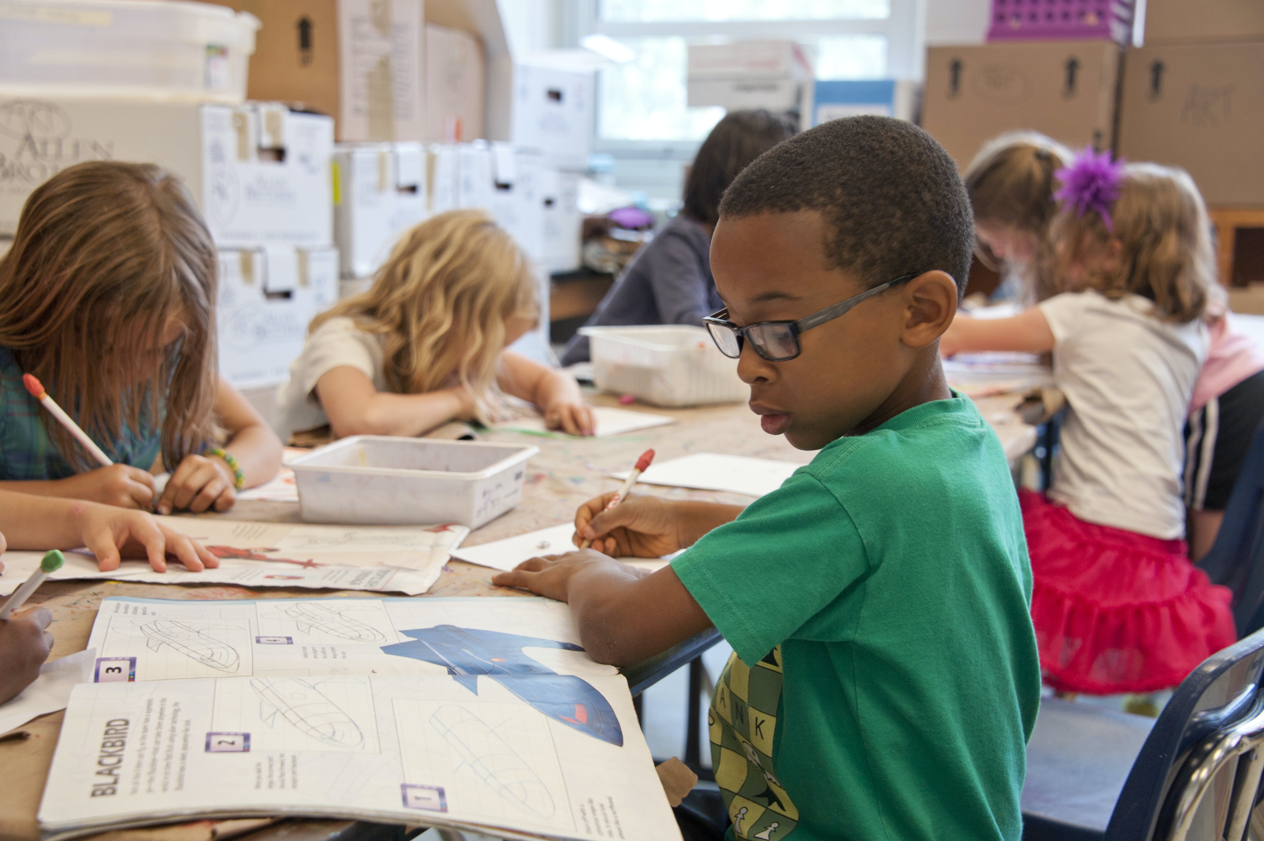 Grunschülerinnen und Grundschüler, die am Tisch in Einzelarbeit arbeiten